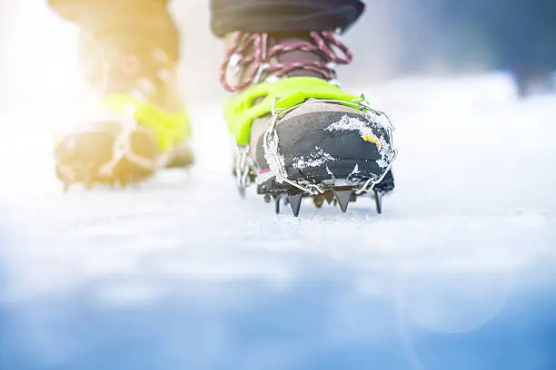 Hiking boots with equipment for ice. Snow like a background and sun. Sun is shining. Moutains and travel.