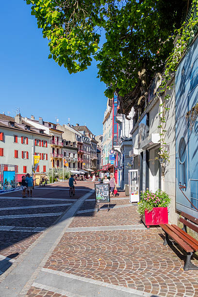 Evian-les-Bains, France. Street view with tourists and a bicycle Evian-les-Bains, France - July 19, 2016: Evian-les-Bains, France. Street view in the old town, with tourists and a man on a bicycle. Evian-les-Bains is a town in the northern part of the department of Haute-Savoie (Region Auvergne-Rhône-Alpes). The town lies on the shores of Lake Geneva (Lac Léman in French), that France is sharing with Switzerland. It is a high-class spa town and its springs are famous all over the world. In the "belle époque", noble houses and luxurious villas were built on the hills and on the lakeshore, including luxurious hotels and a casino. Evian has been visited, for more than two centuries, by kings, artists, and celebrities. evian les bains stock pictures, royalty-free photos & images