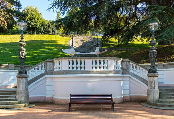Evian-les-Bains, France. Public garden near the source Cachat Evian-les-Bains, France - July 19, 2016: Public garden with staircase, bench and two lampposts near the source Cachat - former fountain of St. Catherine. evian les bains stock pictures, royalty-free photos & images