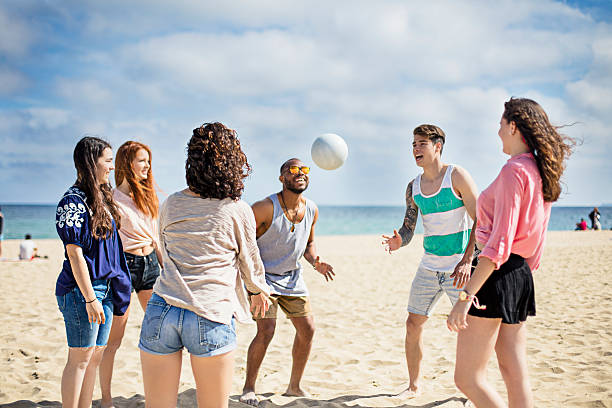 группа друзей, играющих в волейбол на пляже - men summer passing tossing стоковые фото и изображения