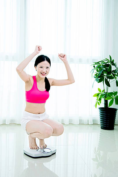 istock Happy woman on weighing scale 636250432
