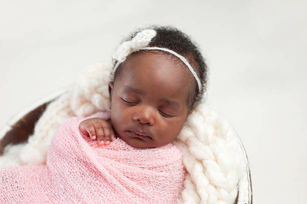 Newborn Baby Girl Sleeping in Bowl Portrait of a one month old, sleeping, newborn, baby girl. She is swaddled in pink and sleeping in a tiny bucket. cute black babys stock pictures, royalty-free photos & images