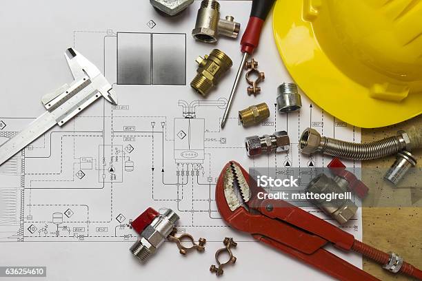 Office Desk With Hydraulic Fittings Helmet And Project Design Stock Photo - Download Image Now