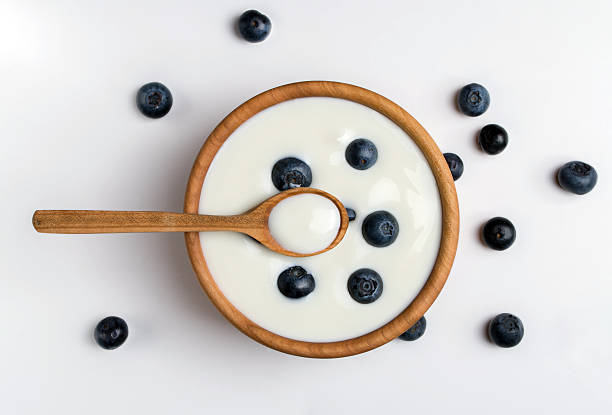 istock White yogurt in natural wooden bowl with blueberries. 636255308