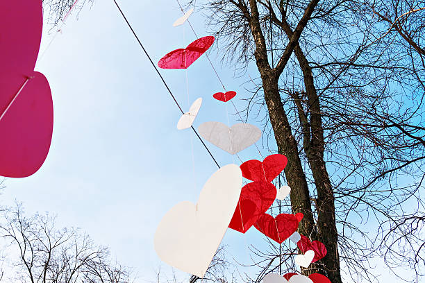 trees in the park are decorated with white and red hearts.