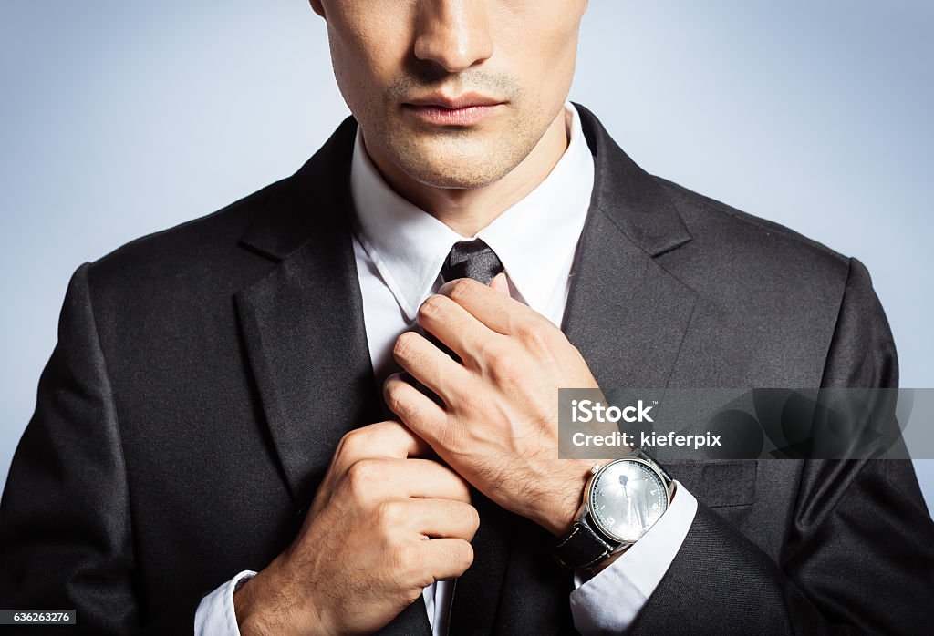 Man in the suit fixing his tie Man in the suit fixing his tie. Business and fashion concept.  Men Stock Photo