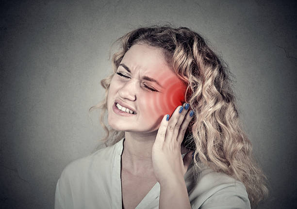 Tinnitus. Sick female having ear pain touching head Tinnitus. Closeup up side profile sick female having ear pain touching her painful head isolated on gray background neuralgia stock pictures, royalty-free photos & images