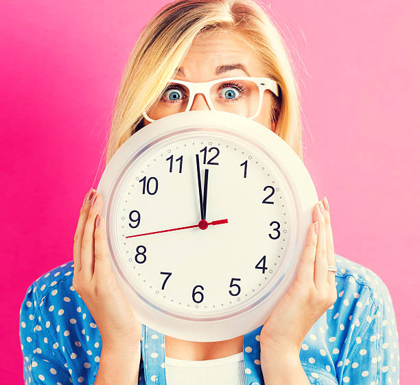 istock Woman holding clock showing nearly 12 636270714