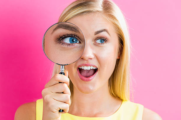 istock Young woman looking through a magnifying glass 636270754