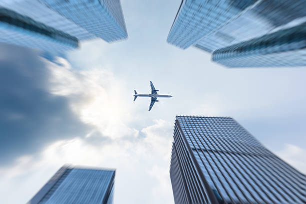istock low angle view of business buildings with plane flying over 636274018