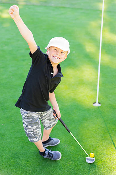 jeune garçon golfeur fête au coucher du soleil - sports flag golf individual sports sports and fitness photos et images de collection