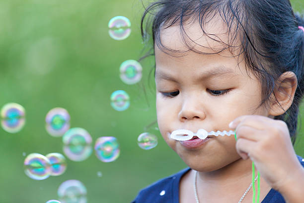 istock Cute asian little girl is blowing soap bubbles 636278346