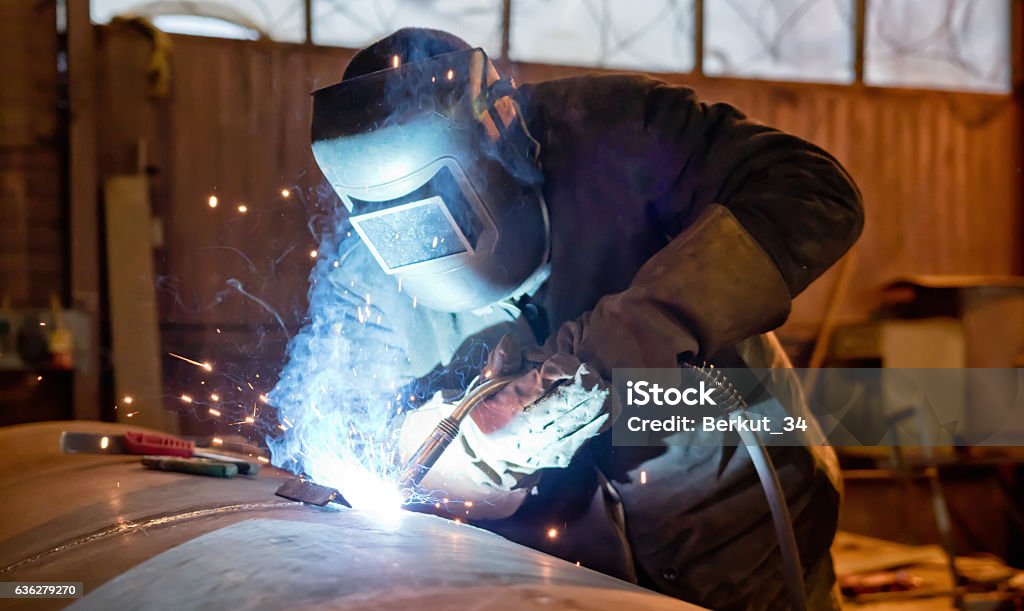 Semi-automatic welding with sparks and smoke Welding large diameter pipe in workshop conditions by the method of semi-automatic welding in shielding gases Welder Stock Photo