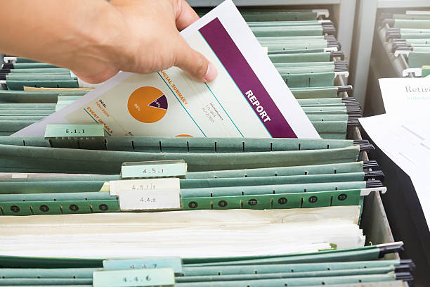 istock Hand holding report file in filing cabinet 636284348