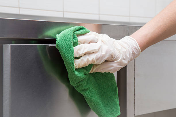 Hand in protective glove with rag cleaning kitchen equipment. Hand in protective glove with rag cleaning kitchen equipment in the professional kitchen. Stainless steel surface. Early spring cleaning or regular clean up. cleaning stove domestic kitchen human hand stock pictures, royalty-free photos & images