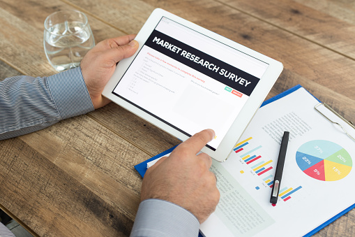 Man holding a tablet showing Market Research Survey concept