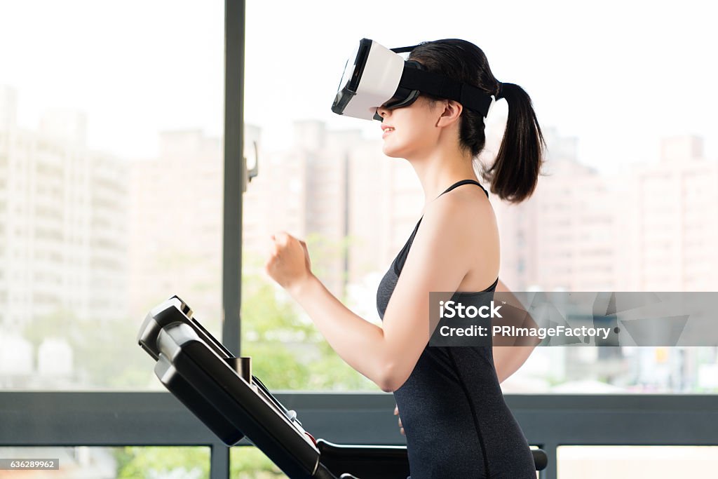 beauty asian woman running treadmill by VR headset glasses beauty asian woman running treadmill by virtual reality. VR headset glasses device. indoors gym background Virtual Reality Stock Photo