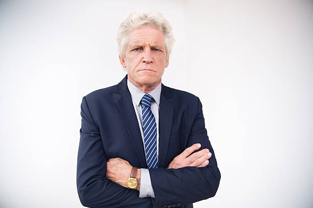 Portrait of displeased senior businessman in suit Portrait of displeased senior Caucasian businessman wearing suit and wristwatch standing with arms crossed and looking at camera wristwatch photos stock pictures, royalty-free photos & images