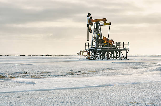 istock Oil pump winter snow. Back light, dark cloudy 636293410