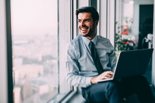 Businessman using a laptop at the window in his office.