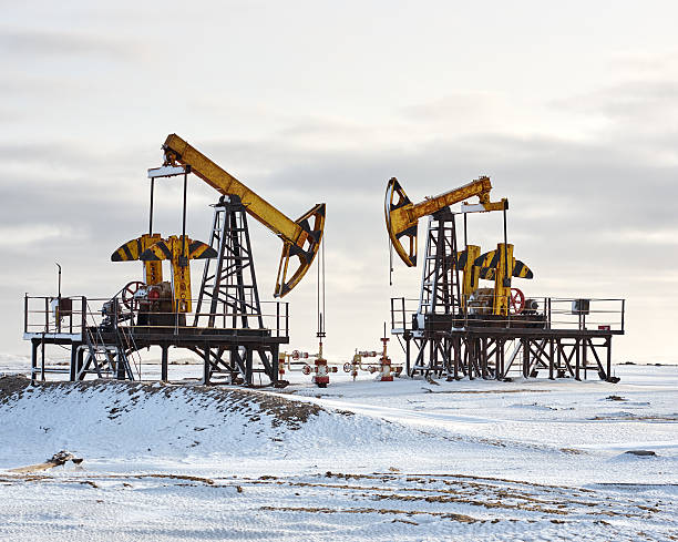 istock Oil pump winter snow. Back light, dark cloudy 636294630