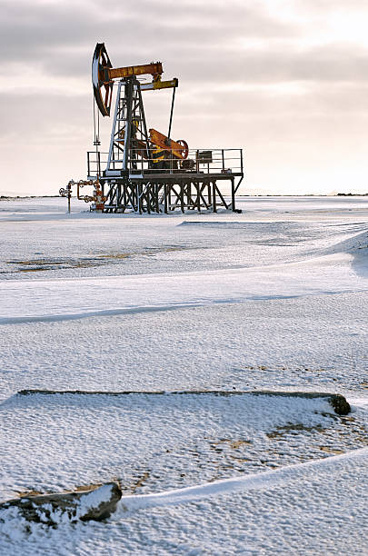 istock Oil pump winter snow. Back light, dark cloudy 636295908