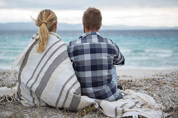 istock Young couple wrapped in blanket on the beach 636296406