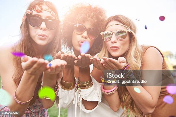 Girls Blowing Some Confetti Pieces Stock Photo - Download Image Now - Coachella Valley, Music Festival, Traditional Festival