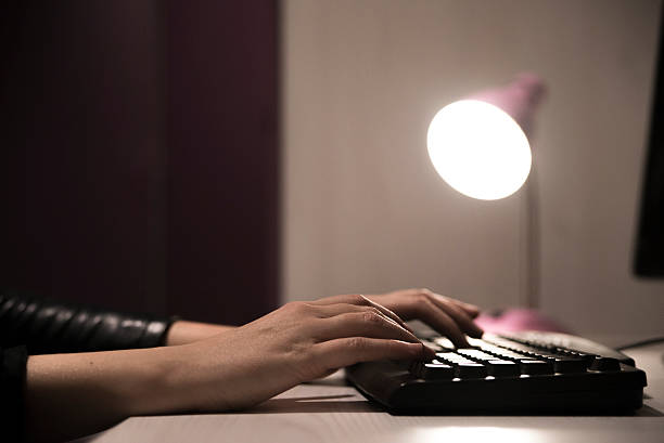 Late night work, Lady working late. Surfing the internet at home, Girl hands typing on keyboard on wooden table at night