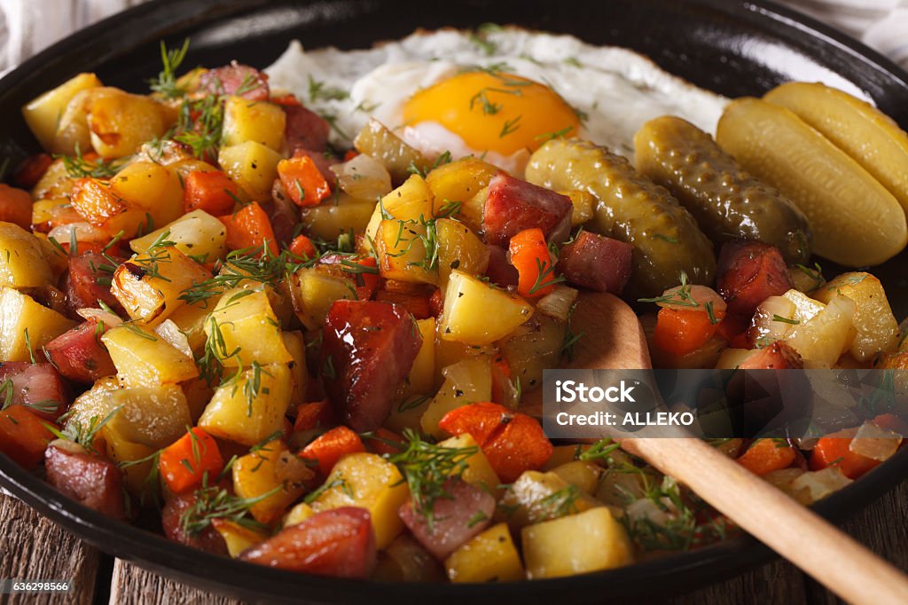 Swedish cuisine: pyttipanna with fried egg and pickled cucumbers Swedish cuisine: pyttipanna with fried egg and pickled cucumbers close-up on a plate. horizontal Adulation Stock Photo