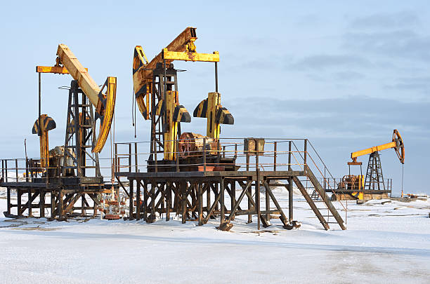 istock Oil pump winter snow. Back light, blue cloudy sky 636298868