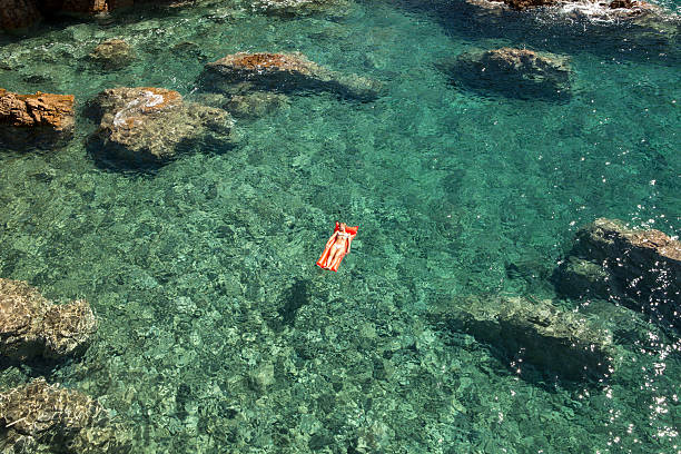바다에서 수영장 매트리스에 떠있는 젊은 여자 - pool raft sea red floating on water 뉴스 사진 이미지