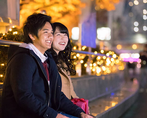 istock Young couple sitting with smile under Christmas lights 636304482
