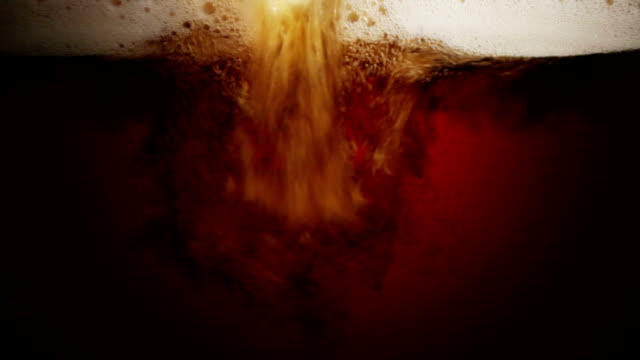 close up scene of pouring dark beer into glass