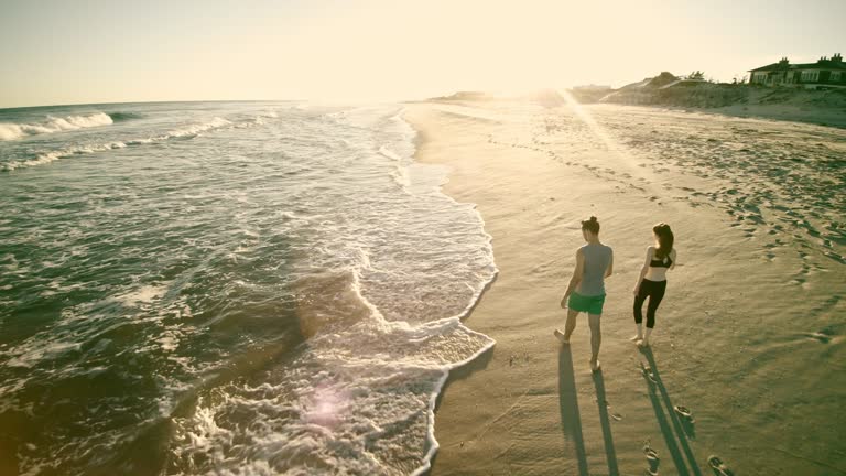 Young man and teenager girl walking together and talking on the beach in Long Island. Aerial footage.