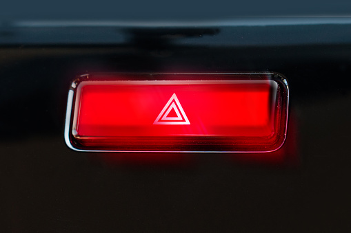 pushed red warning button with triangle pictogram and flasher light.