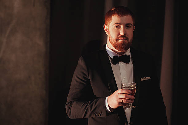 istock Young ginger bearded man holding a vintage glass with red 636314254