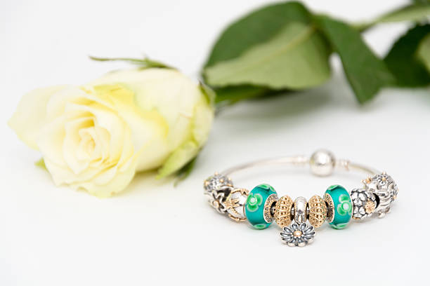 A glass bracelet and a branch of crimson flowers on a wooden blue background.