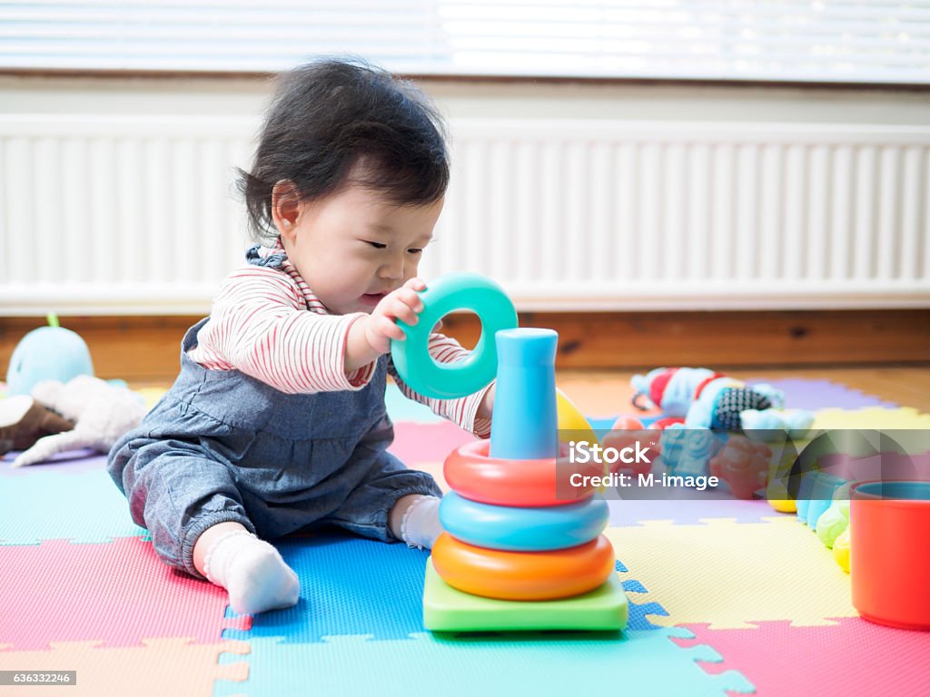 baby girl sitting on play mat  and playing toy Adorable baby girl sitting on play mat  and playing toy at home Baby - Human Age Stock Photo