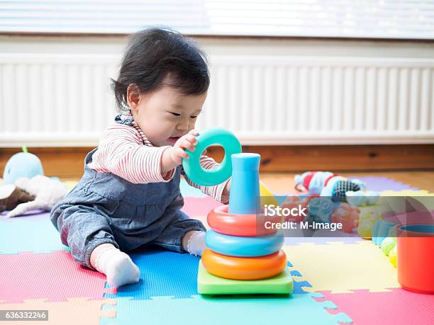 Baby Girl Sitting On Play Mat And Playing Toy Stock Photo - Download Image Now - Baby - Human Age, Playful, Playing