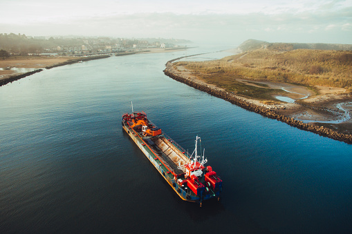 A dredge ship in a river about to end at the sea