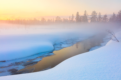 Colorful winter sunset in forest and river with beautiful misty fog, fantastic winter nature landscape