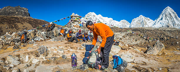 guía sherpa y porteadores al lado de las banderas de oración montañas del himalaya nepal - many colored prayer flags fotografías e imágenes de stock