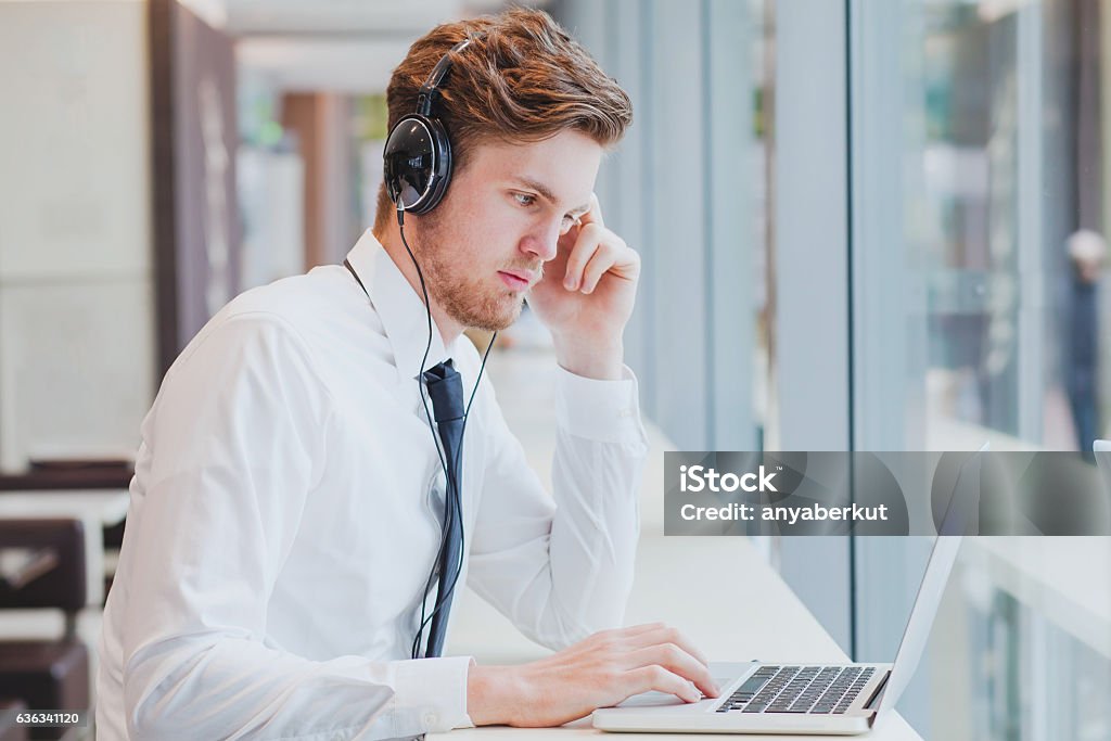 businessman in headphones working with laptop businessman in headphones working with laptop in modern cafe interior E-Learning Stock Photo