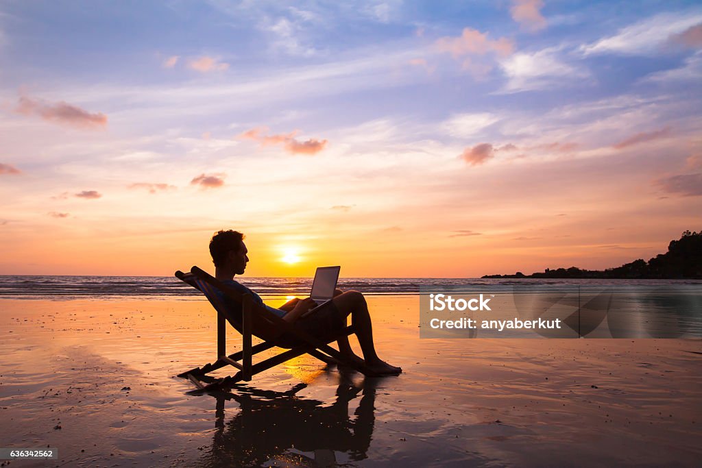 business man with laptop working on the beach silhouette of happy business man with laptop working on the beach Working Stock Photo