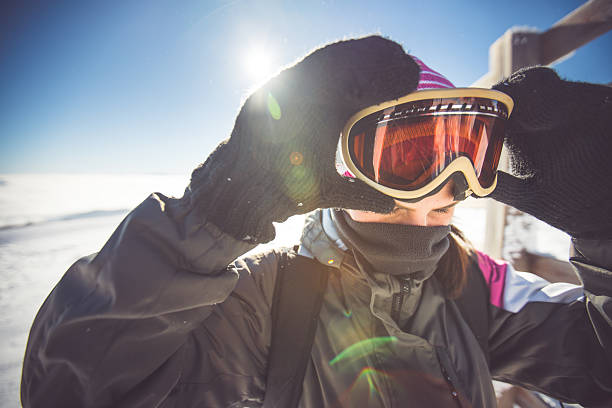 Skiing eyewear Woman putting on skiing goggles ski goggles stock pictures, royalty-free photos & images