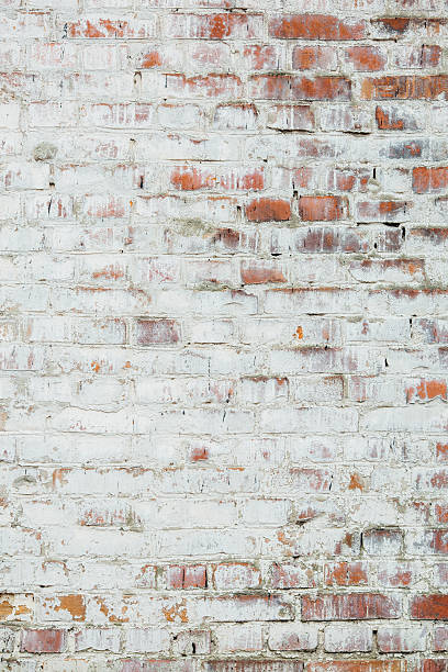 istock Poorly painted wall of damaged red brick with white paint 636344462