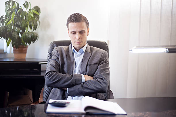 istock Businessman sitting with crossed arms looking at notebook 636345332