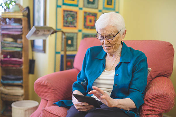 istock Elderly woman reading on a digital tagblet in her 636345526