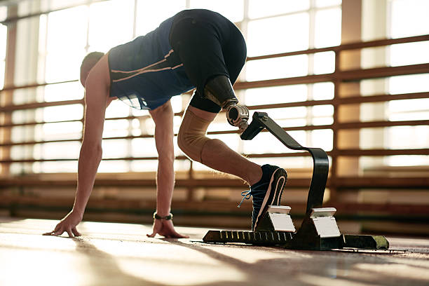 Athlete with prosthetic leg at running track Rear view of man with prosthetic leg crouched in starting position on running track athlete with disabilities photos stock pictures, royalty-free photos & images